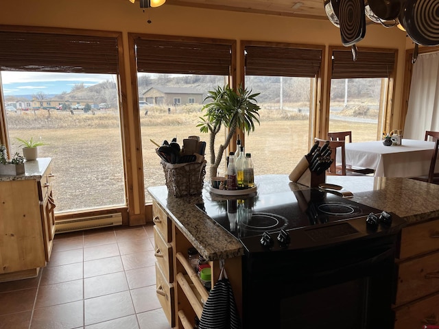 kitchen featuring plenty of natural light, light tile patterned floors, black range with electric stovetop, and dark stone counters