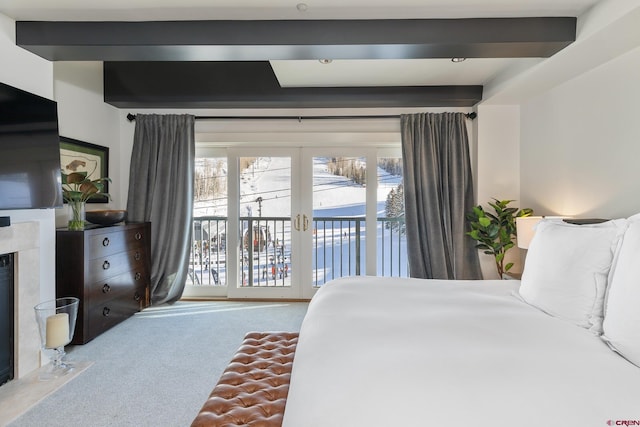 bedroom with access to outside, beam ceiling, a premium fireplace, and carpet floors