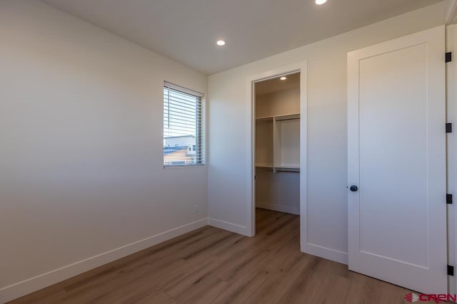 unfurnished bedroom featuring a closet, a walk in closet, and light hardwood / wood-style flooring