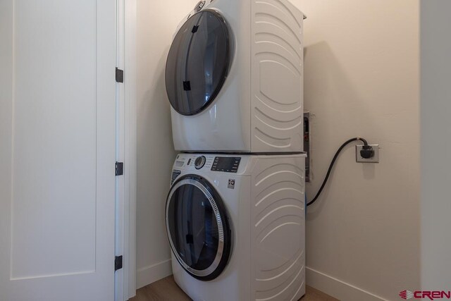 clothes washing area with stacked washer and dryer and light hardwood / wood-style flooring