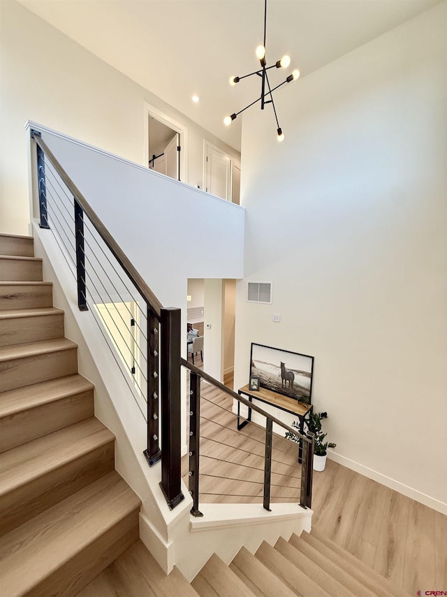 staircase featuring an inviting chandelier and hardwood / wood-style floors