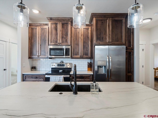 kitchen featuring sink, hanging light fixtures, appliances with stainless steel finishes, and tasteful backsplash