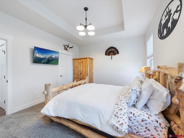 carpeted bedroom with a raised ceiling and an inviting chandelier