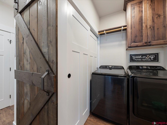 laundry area with washer and dryer, cabinets, light hardwood / wood-style flooring, and a barn door