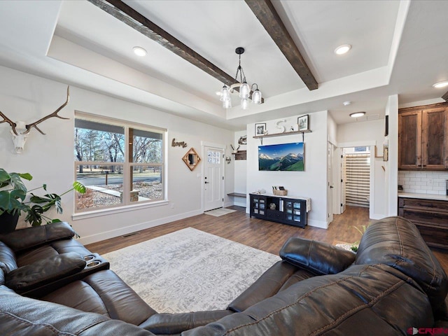 living room with an inviting chandelier, wood-type flooring, and a raised ceiling