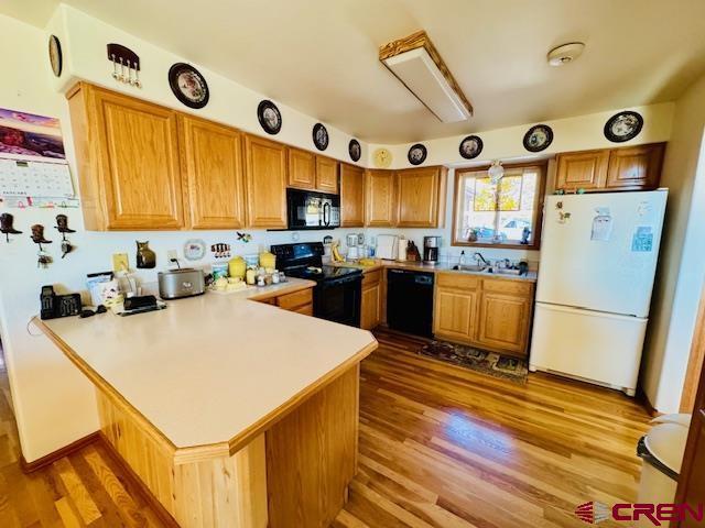 kitchen featuring sink, dark hardwood / wood-style floors, black appliances, and kitchen peninsula