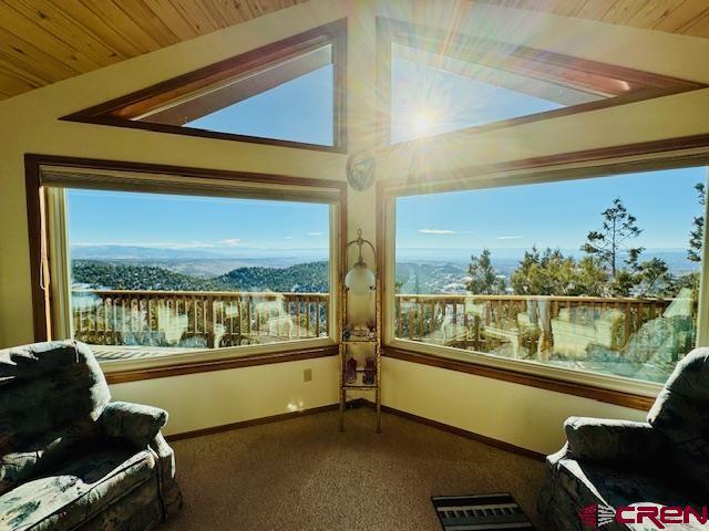 sunroom with a mountain view, wooden ceiling, a wealth of natural light, and vaulted ceiling