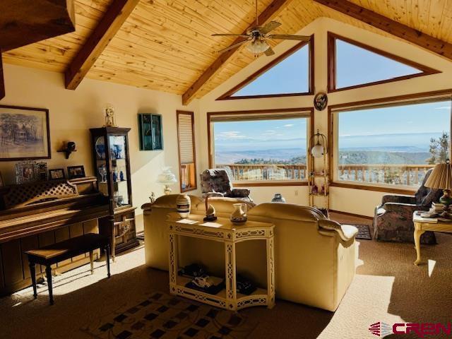 living room featuring beamed ceiling, ceiling fan, high vaulted ceiling, a mountain view, and wooden ceiling