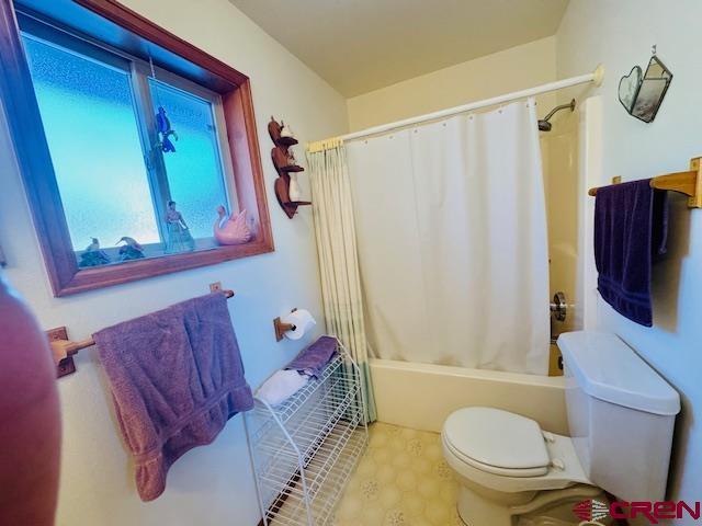 bathroom featuring toilet and shower / bathtub combination with curtain