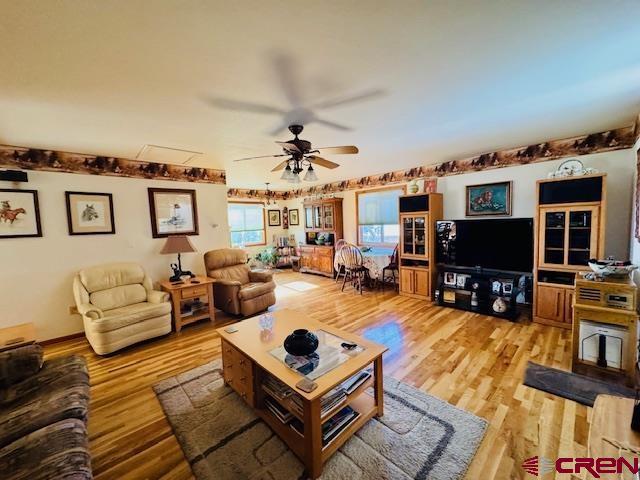 living room featuring ceiling fan and light hardwood / wood-style floors