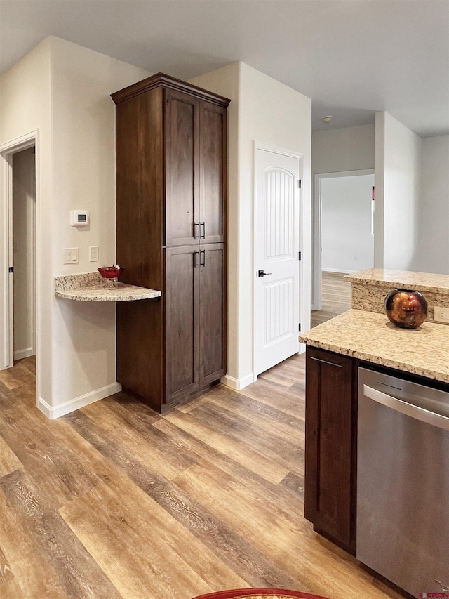 kitchen with light stone countertops, dark brown cabinetry, dishwasher, and light wood-type flooring