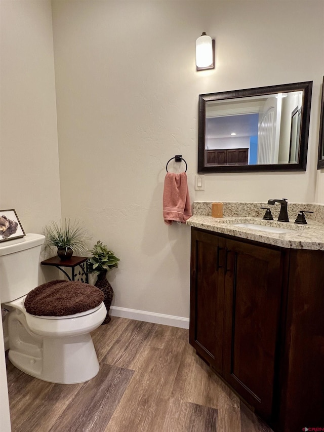 bathroom featuring wood-type flooring, toilet, and vanity