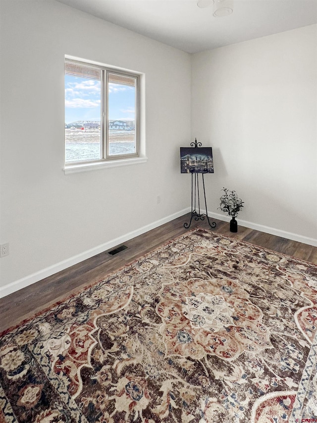 empty room featuring a water view and dark wood-type flooring