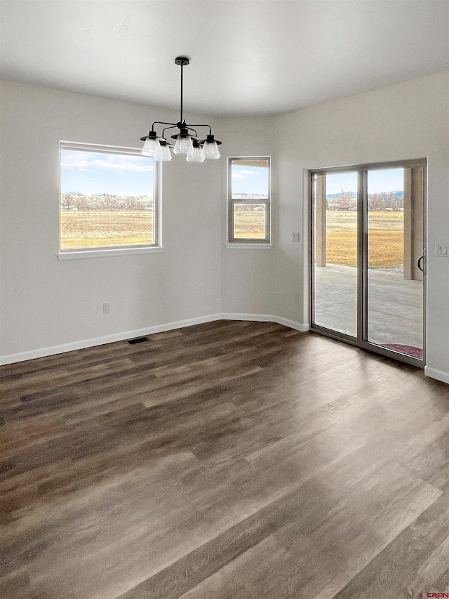 unfurnished dining area with dark wood-type flooring and a chandelier