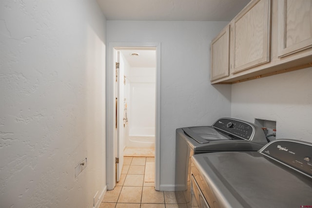 laundry room featuring cabinets, light tile patterned floors, and washing machine and clothes dryer