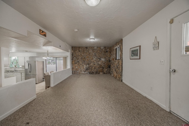 interior space featuring light colored carpet, a chandelier, and a textured ceiling