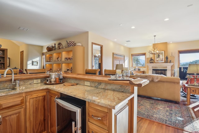 kitchen with decorative light fixtures, light stone countertops, beverage cooler, and sink