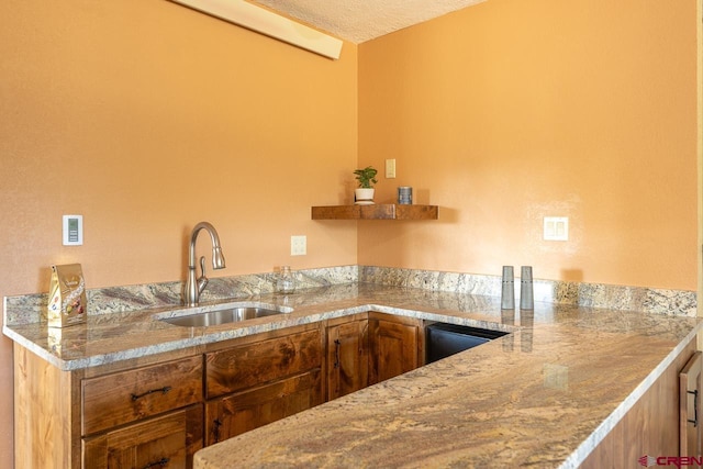 kitchen featuring light stone countertops, sink, and a textured ceiling