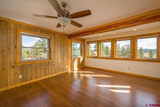 unfurnished room with ceiling fan, hardwood / wood-style flooring, and wooden walls