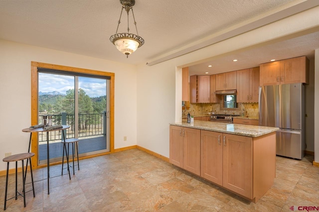 kitchen featuring decorative light fixtures, backsplash, kitchen peninsula, light stone countertops, and appliances with stainless steel finishes