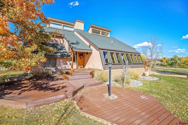 rear view of house with a deck, a yard, and a sunroom