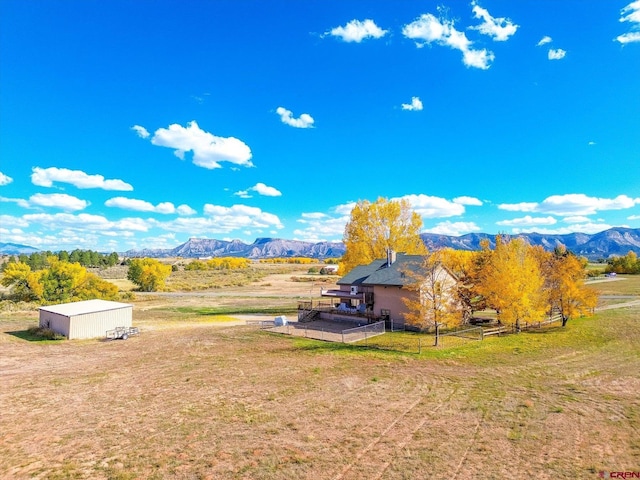 exterior space featuring a rural view, a mountain view, and an outdoor structure