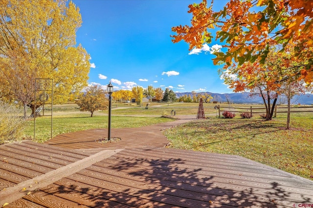 view of property's community featuring a rural view, a deck with mountain view, and a yard