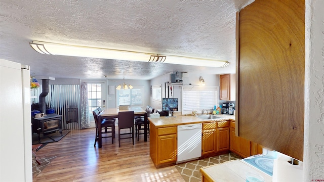 kitchen featuring wood-type flooring, sink, hanging light fixtures, tile countertops, and white dishwasher