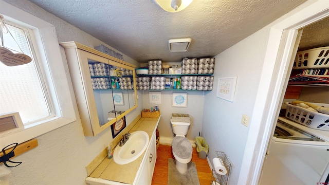 bathroom featuring toilet, vanity, a wealth of natural light, and a textured ceiling