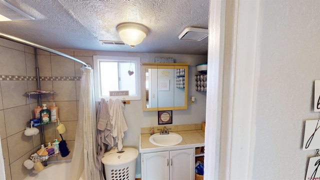 bathroom featuring walk in shower, vanity, and a textured ceiling