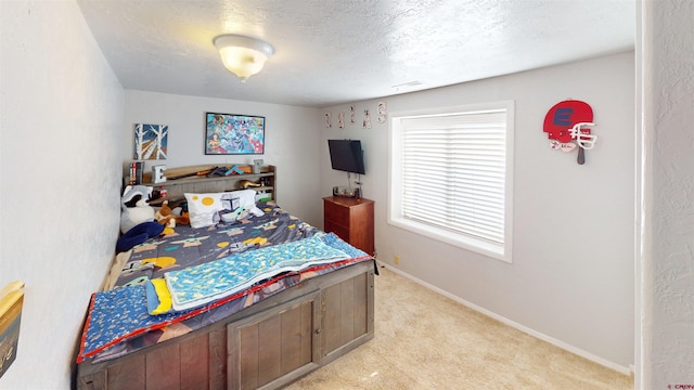 bedroom featuring light carpet and a textured ceiling