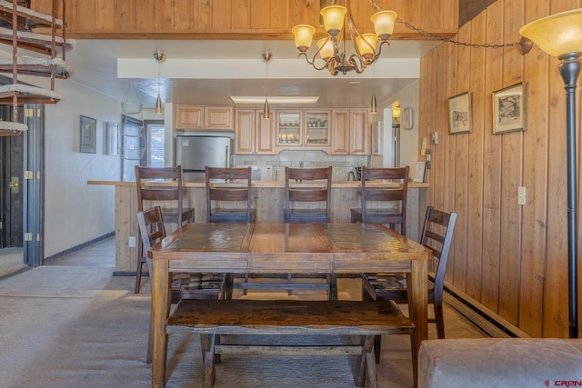 carpeted dining space with a notable chandelier, wood walls, and a baseboard radiator