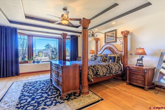 bedroom with ceiling fan, hardwood / wood-style floors, and a tray ceiling