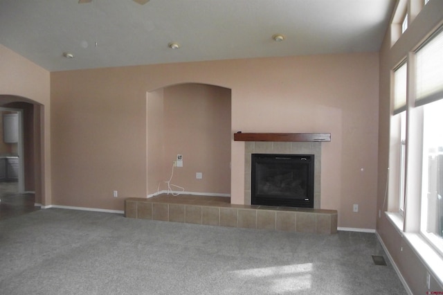 unfurnished living room with carpet, a tile fireplace, and a healthy amount of sunlight