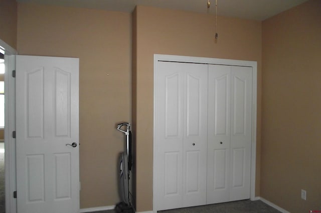 unfurnished bedroom with dark carpet and a closet