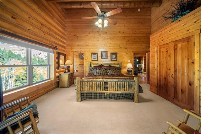 carpeted bedroom with ceiling fan, a towering ceiling, wood walls, and beamed ceiling