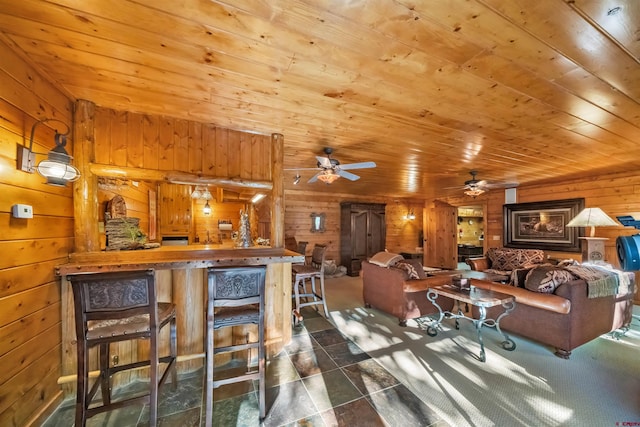 dining room featuring ceiling fan, wood ceiling, wooden walls, and bar area