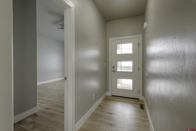 doorway featuring light wood-type flooring, a healthy amount of sunlight, baseboards, and visible vents