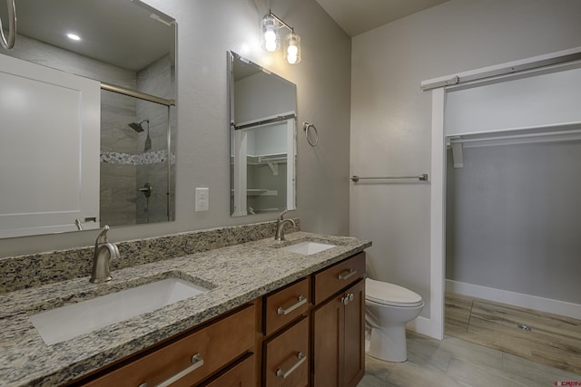 bathroom with a stall shower, a walk in closet, a sink, and double vanity