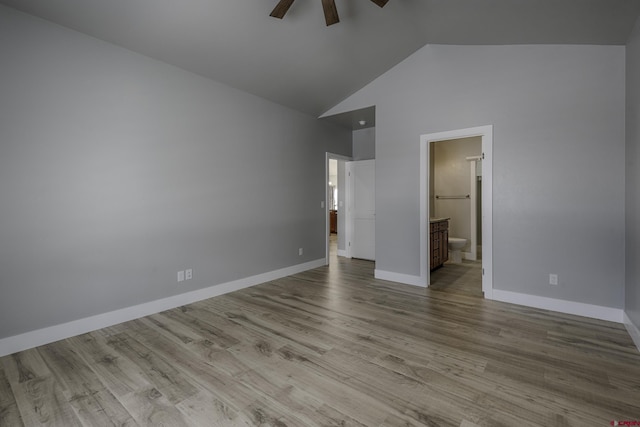 unfurnished bedroom featuring light wood-type flooring, high vaulted ceiling, baseboards, and connected bathroom