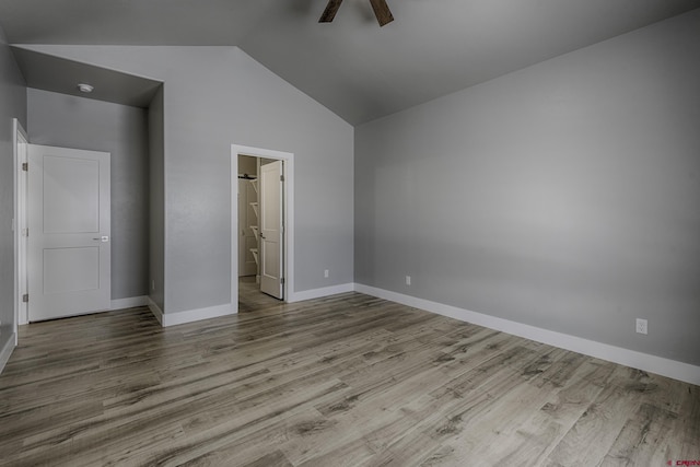 unfurnished bedroom with light wood finished floors, ensuite bathroom, ceiling fan, high vaulted ceiling, and baseboards