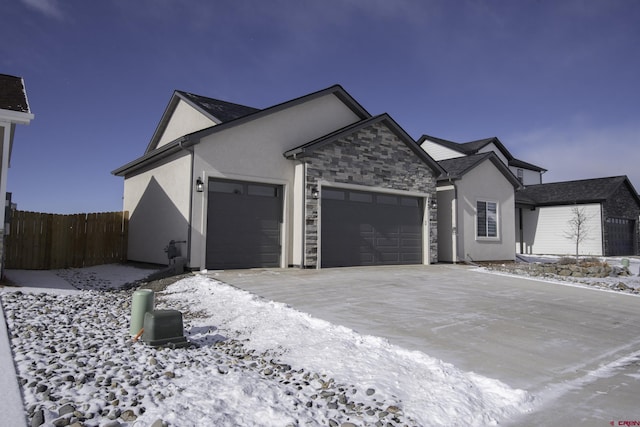 single story home featuring driveway, stone siding, an attached garage, fence, and stucco siding