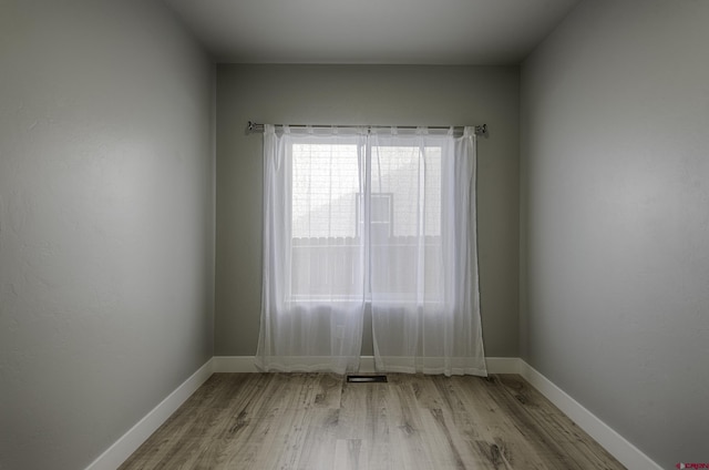 empty room featuring light wood-type flooring, baseboards, and visible vents