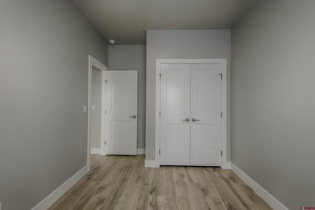 unfurnished bedroom with light wood finished floors, baseboards, and a closet