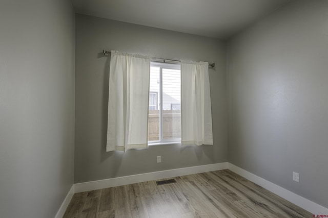 unfurnished room featuring light wood-style floors, visible vents, and baseboards