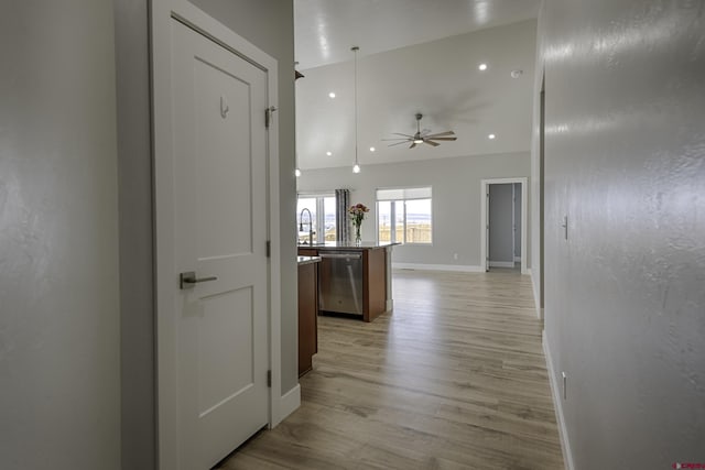 hallway with light wood-type flooring, a sink, and baseboards