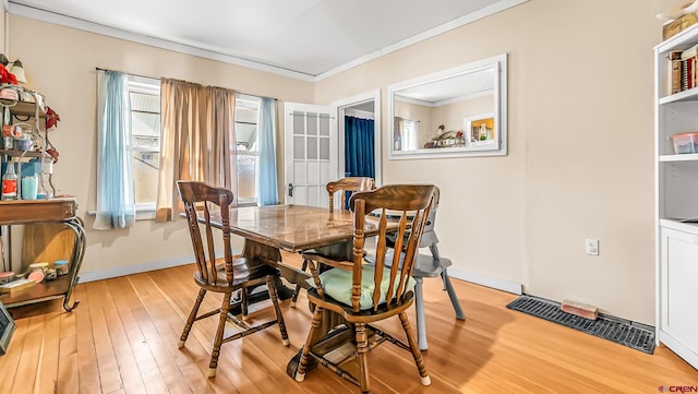 dining space with light hardwood / wood-style flooring and ornamental molding