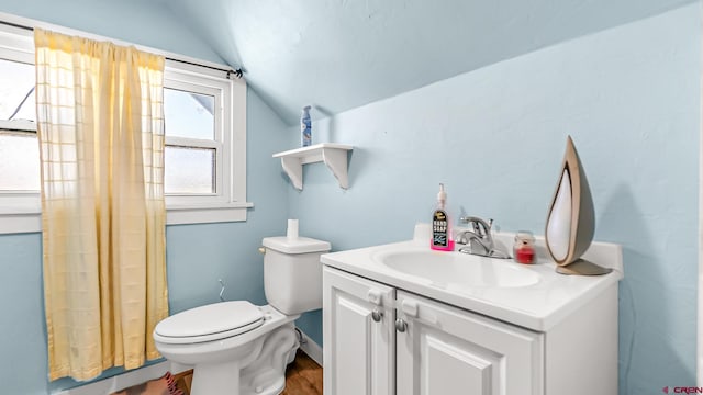 bathroom with toilet, lofted ceiling, and vanity