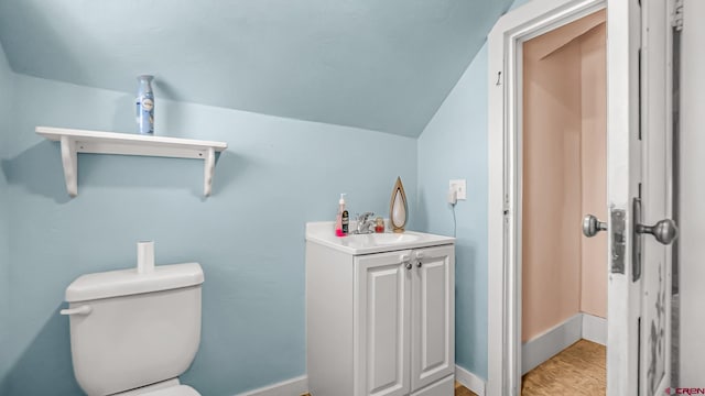 bathroom featuring hardwood / wood-style floors, toilet, vanity, and lofted ceiling