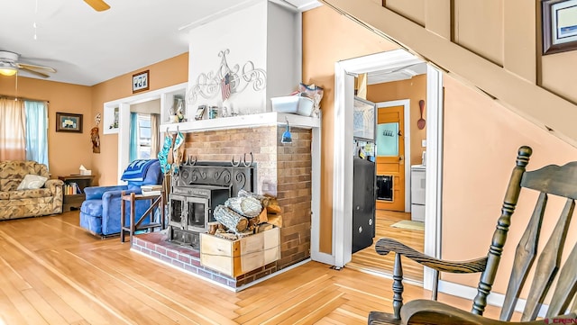 living room with ceiling fan, light parquet flooring, and a wood stove